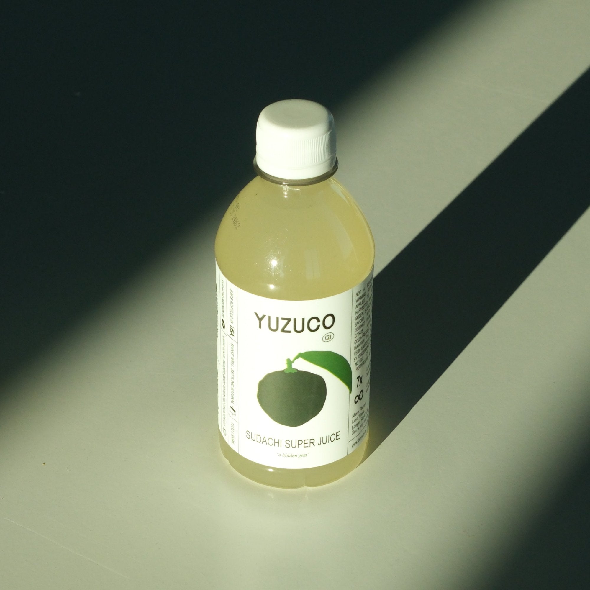 Sudachi Super Juice (12oz) with high contrast light and shadows on a greyish green background