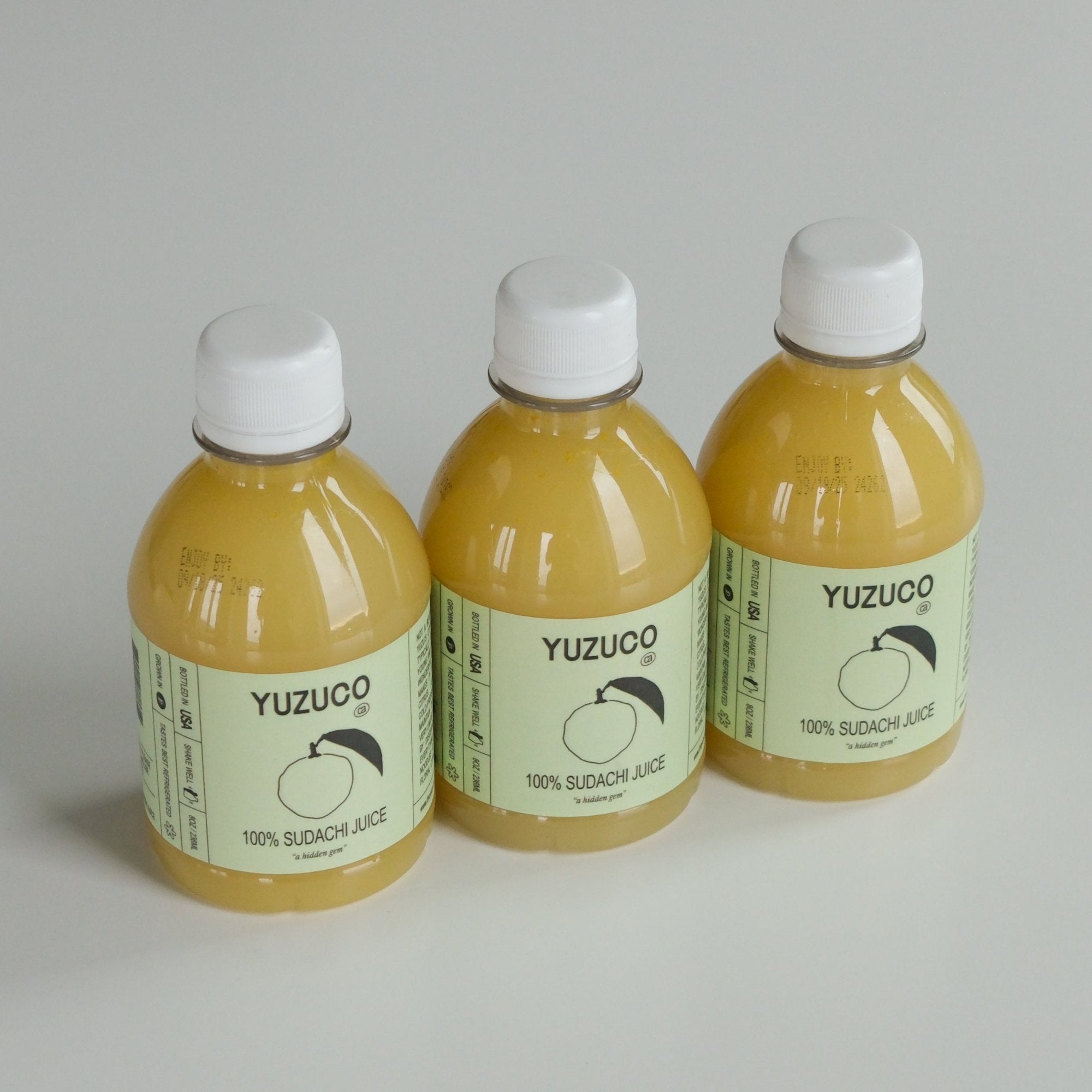 3 bottles of 8oz 100% Sudachi Juice lined up on a grey background.