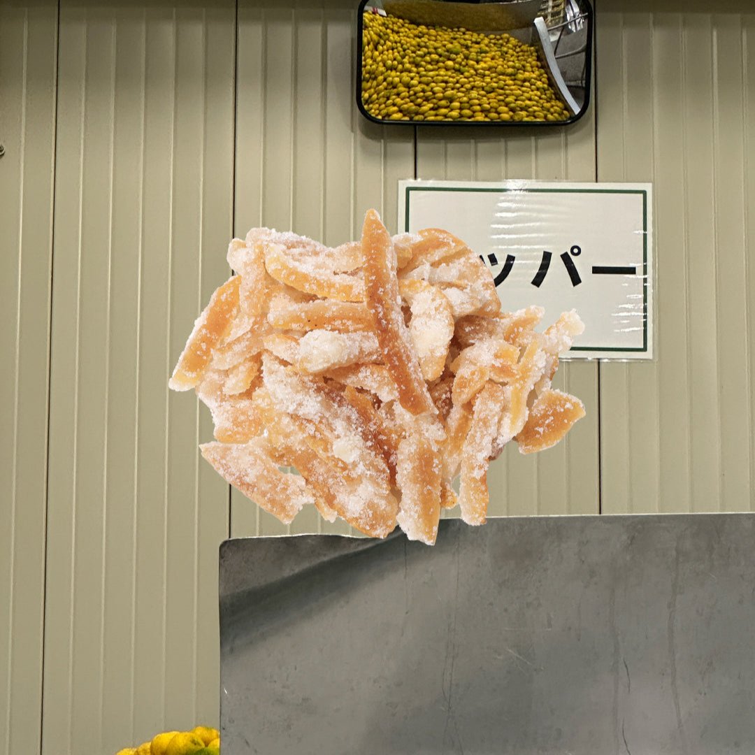 candied yuzu peel over image of yuzu squeezing factory